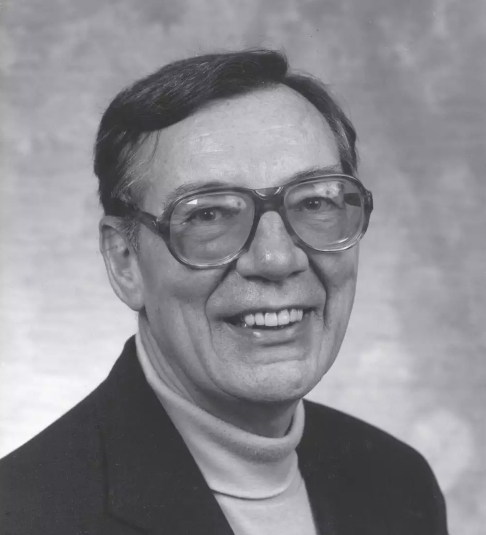 black and white photo of man with glasses smiling